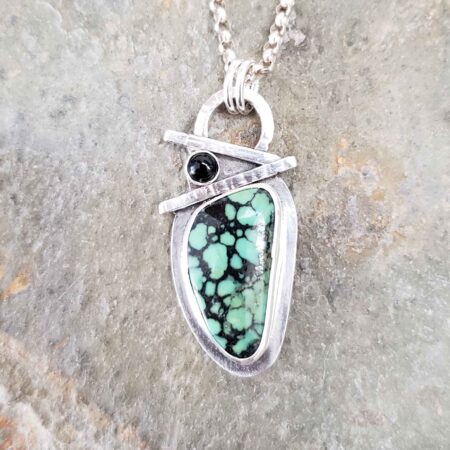 Turquoise with black veins accented with onyx in this sterling silver pendant.