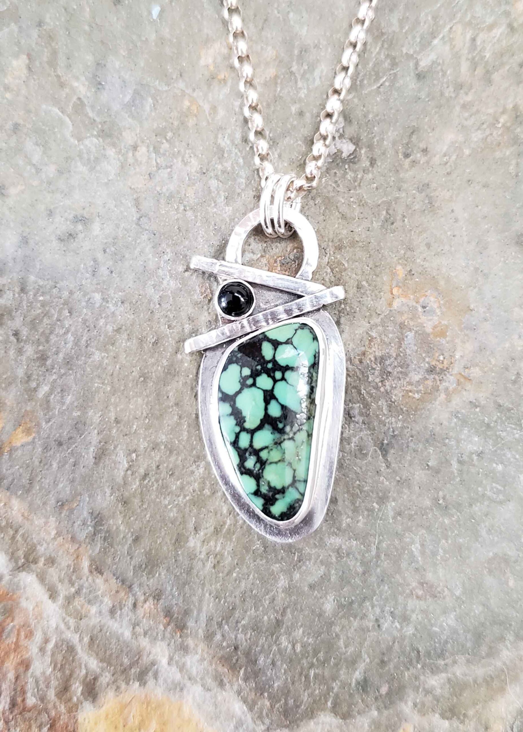 Turquoise with black veins accented with onyx in this sterling silver pendant.