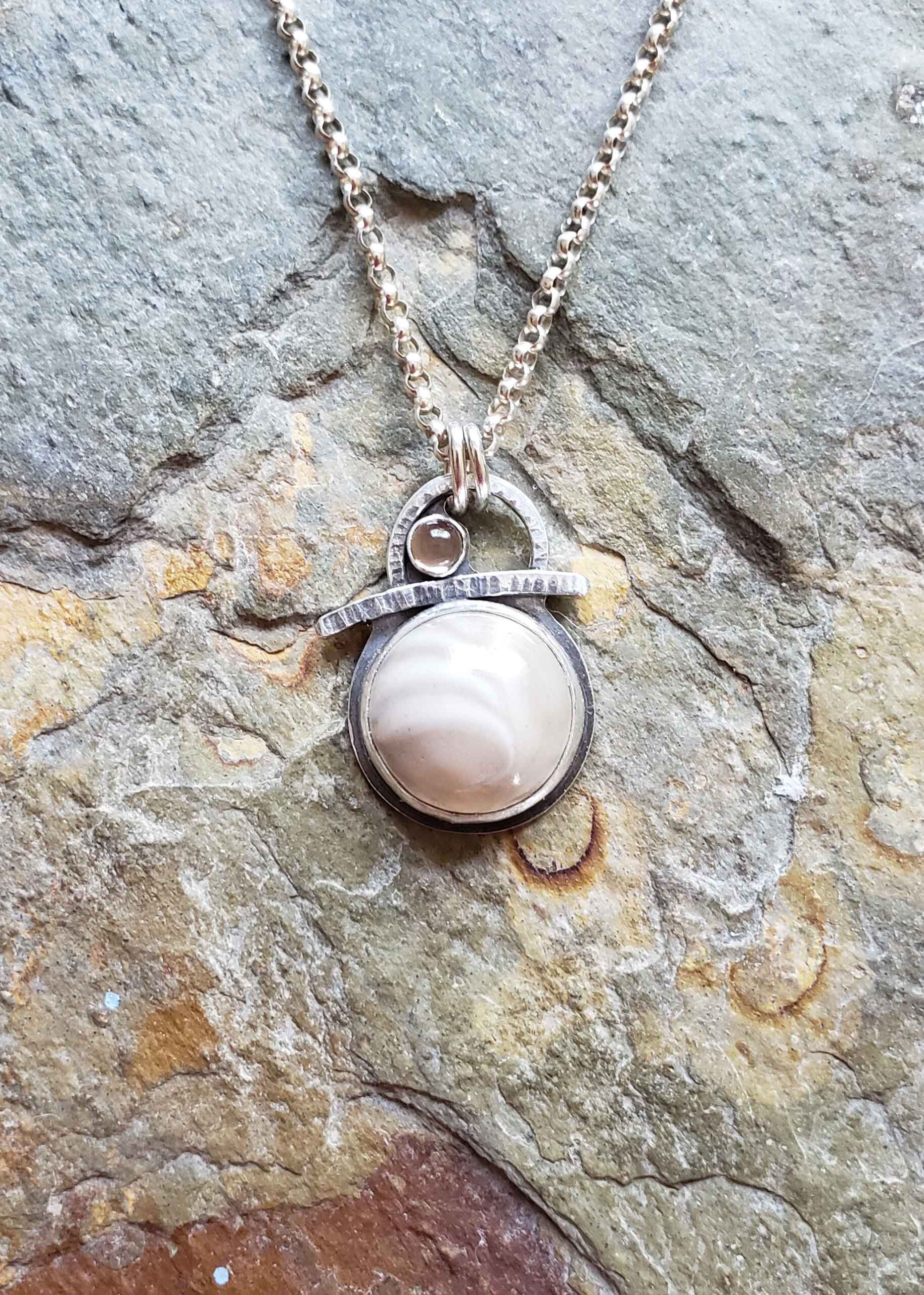 Petite silver pendant in creams and browns by Dona Miller.