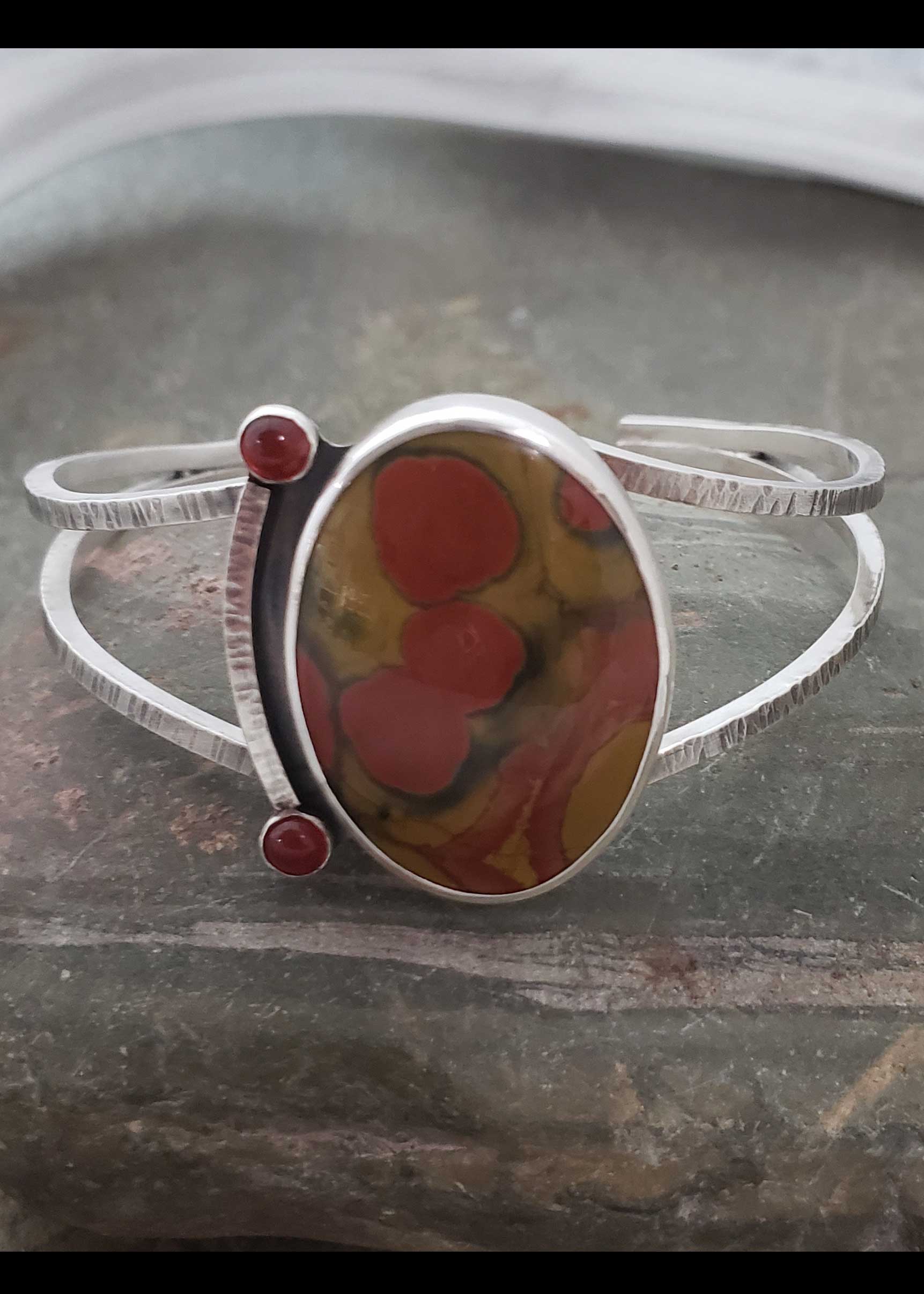 reds and golds are the center piece of this silver cuff bracelet by Dona Miller